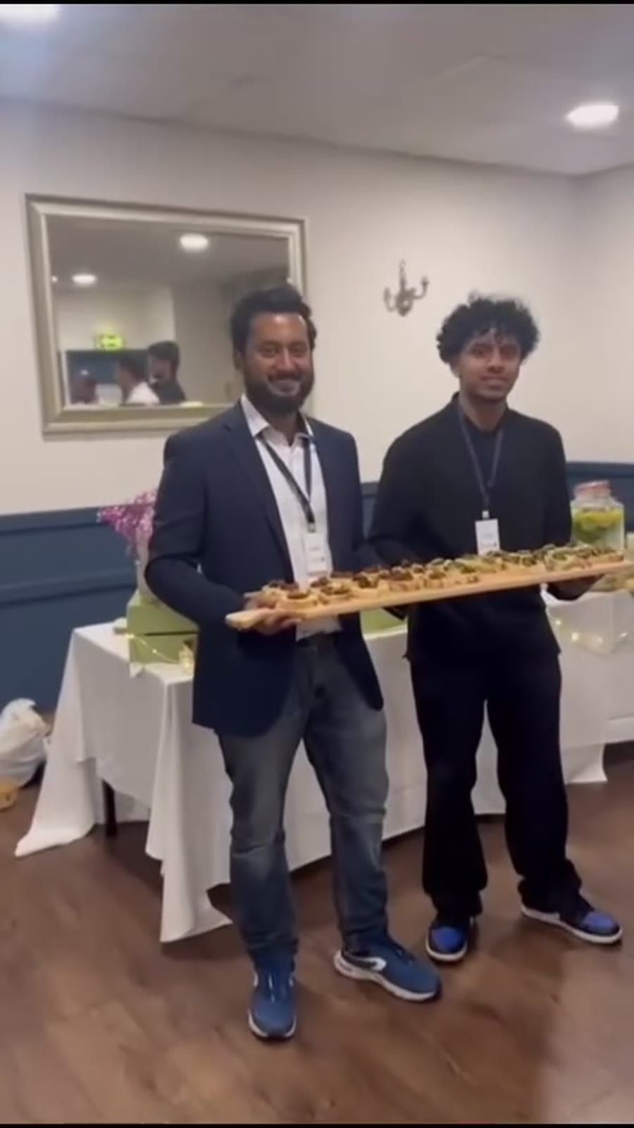 Two of the Calvary team holding a long paddle of canapés