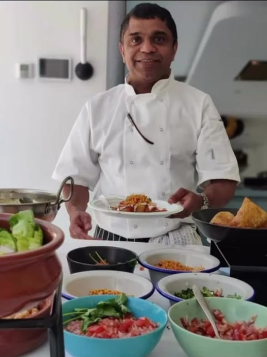 Chef Bijomon K Jacob in chef's whites, holding a plate at his chaat station