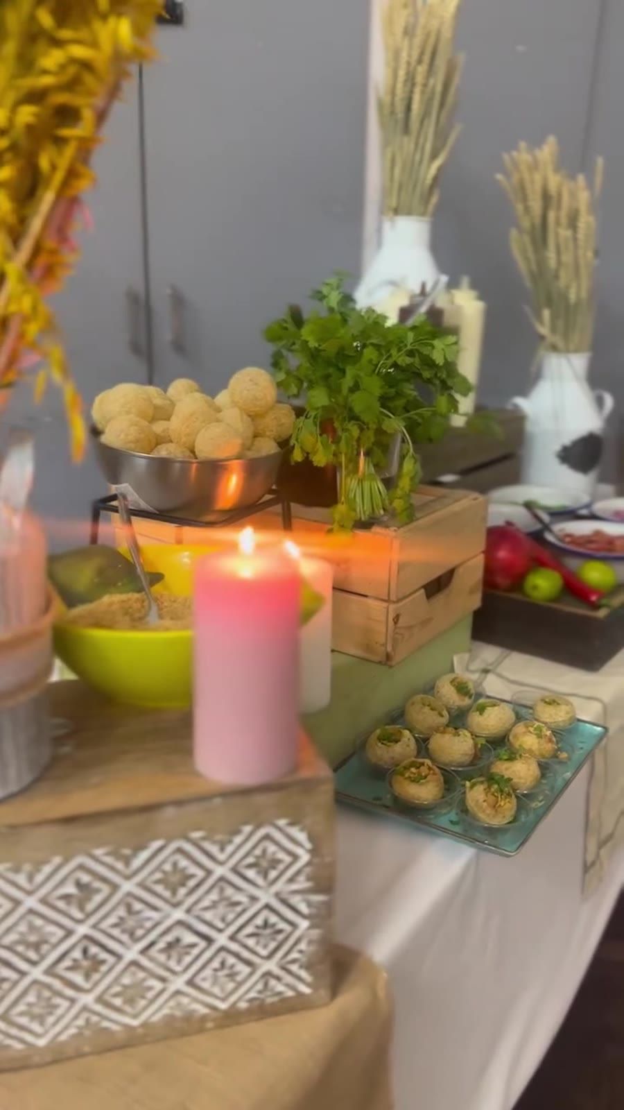 A rustic street food station with wooden crates, wheat sheaves, candles and bowls of snacks